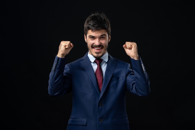 Free photo front view of young proud and emotional bearded man enjoying his succeess on isolated dark wall