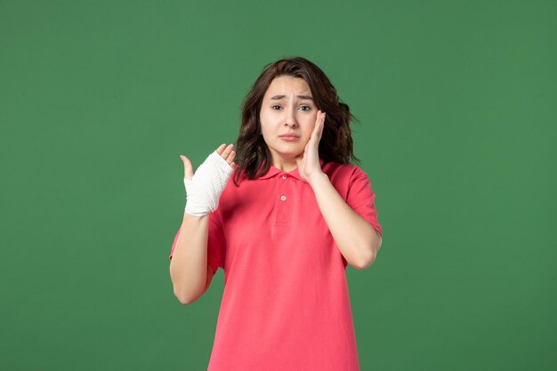 Front view young saleswoman with bandage on her hurt hand on a green surface