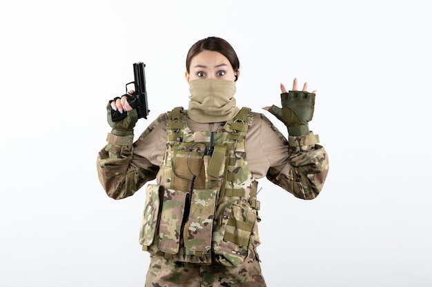 Free Photo front view of young soldier in camouflage surrending with gun on white wall