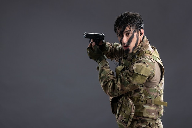 Free Photo front view young soldier fighting in camouflage with gun on dark wall