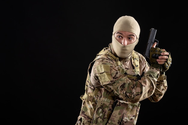 Free Photo front view young soldier in uniform with gun black wall