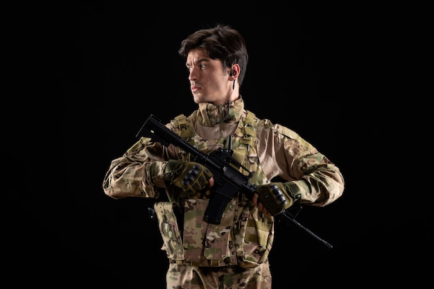 Free photo front view young soldier in uniform with rifle on black wall