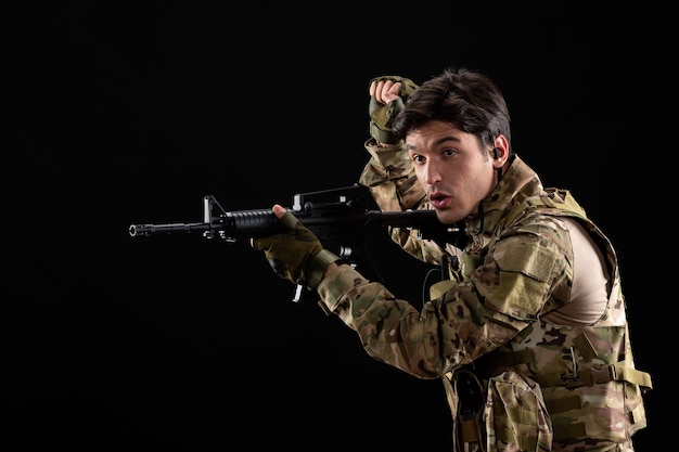 Free Photo front view young soldier in uniform with rifle on black wall