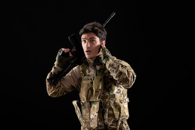 Free Photo front view of young soldier in uniform with rifle on black wall