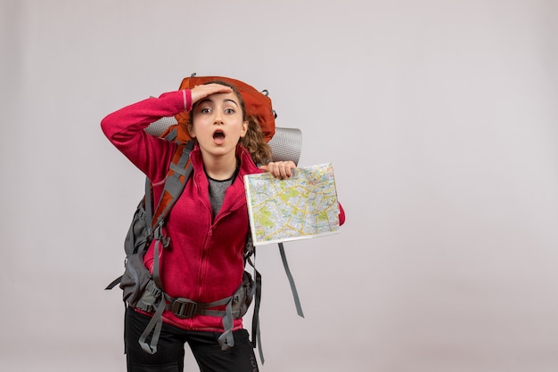 Front view young traveller with big backpack holding map looking at something