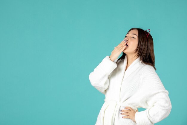 front view of young woman in bathrobe on blue wall