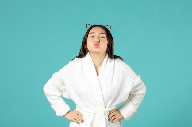 front view of young woman in bathrobe on blue wall