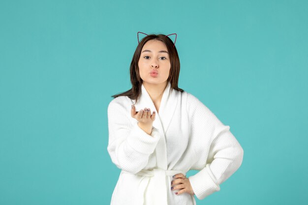 front view of young woman in bathrobe on blue wall