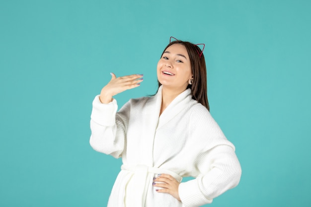 front view of young woman in bathrobe on blue wall