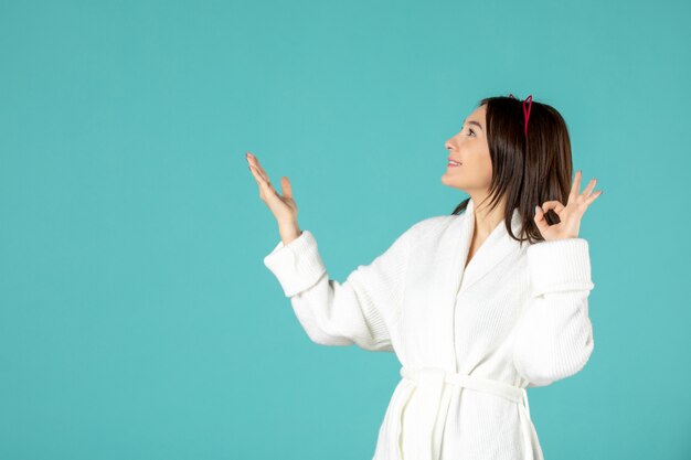 front view of young woman in bathrobe on blue wall