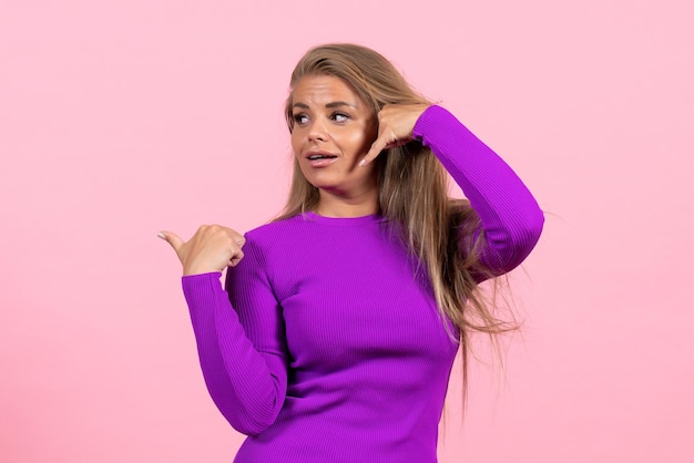 Free photo front view of young woman in beautiful purple dress posing on pink wall