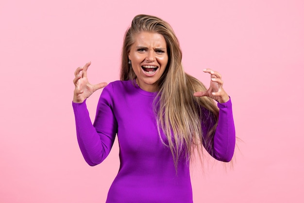 Free photo front view of young woman in beautiful purple dress posing on pink wall