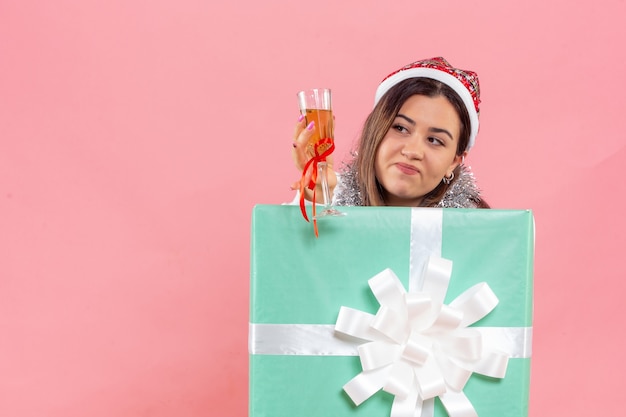 Free photo front view of young woman celebrating xmas with drink on a pink wall