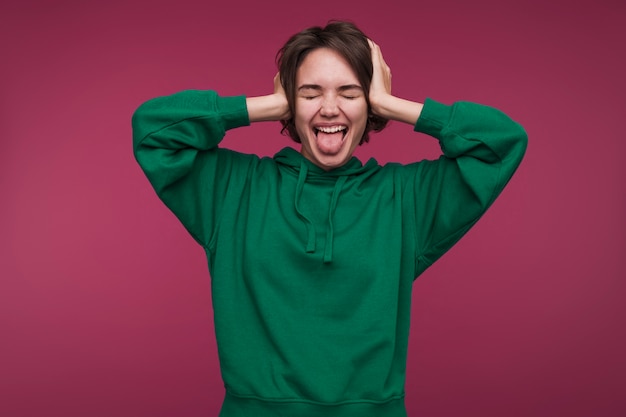 Front view of a young woman covering her ears and being silly