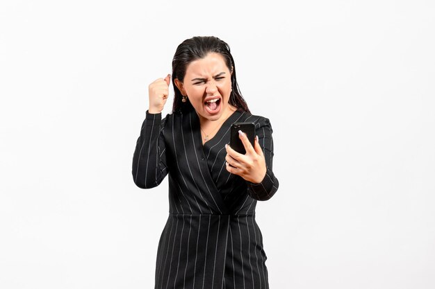 Front view young woman in dark strict suit holding her phone screaming on white background woman lady fashion office worker job beauty