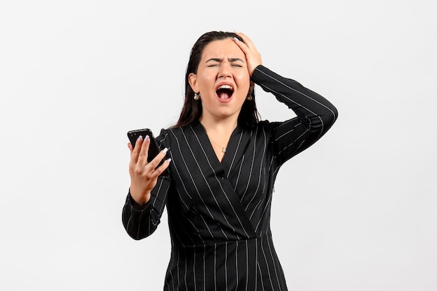 Front view young woman in dark strict suit holding phone with painful face on a white background woman lady fashion worker job beauty