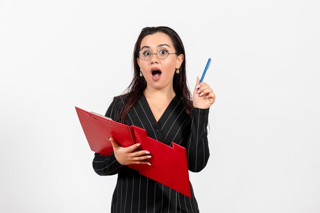 Front view young woman in dark strict suit holding red file on white background office beauty business job fashion female