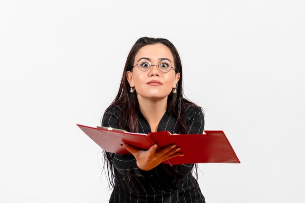 Front view young woman in dark strict suit holding red file on the white background office business job fashion female document