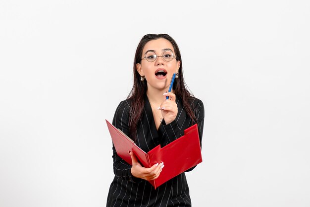 Front view young woman in dark strict suit holding red file on white background office business job fashion female documents