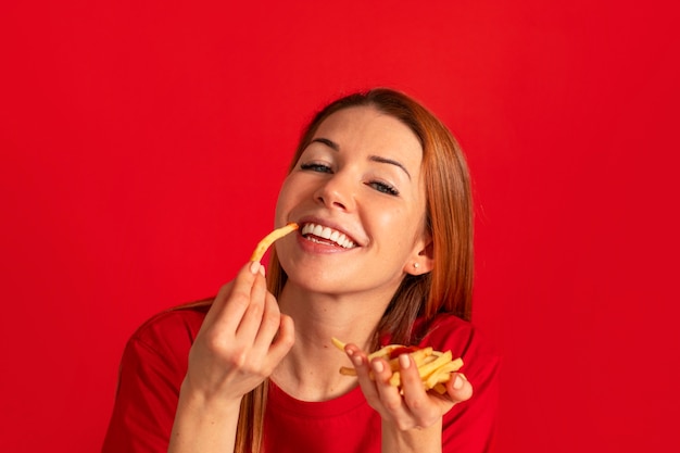 Free photo front view young woman eating fries