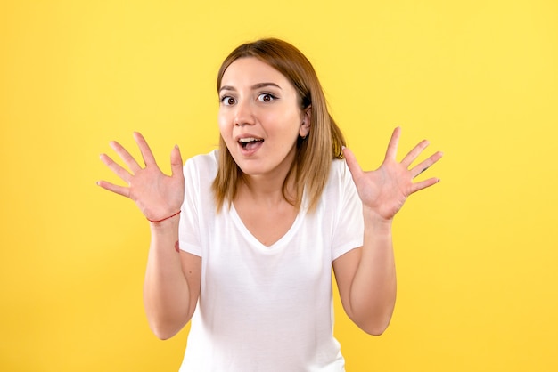 Front view of young woman excited on yellow wall