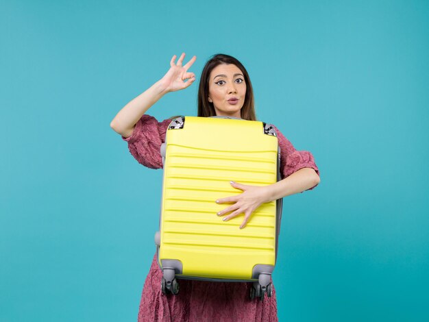 Front view young woman going in vacation and holding big bag on blue desk summer journey sea vacation voyage woman