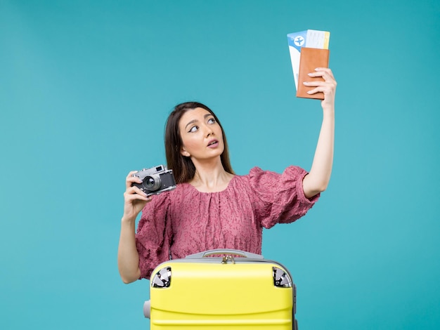 Front view young woman going in vacation holding camera and tickets on blue background journey vacation woman abroad sea