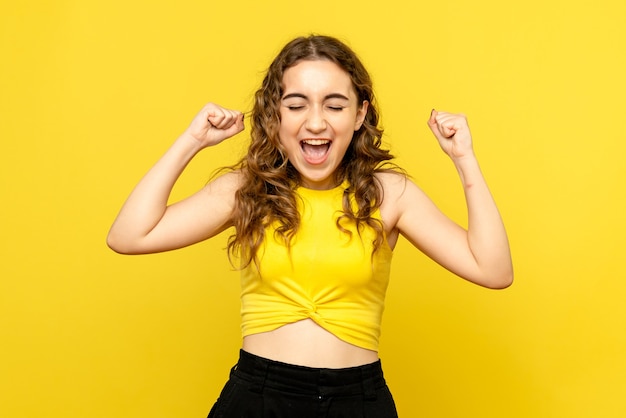 Free Photo front view of young woman happily rejoicing on yellow wall