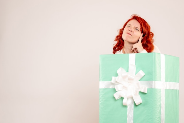 Free photo front view of young woman hiding inside present on white wall