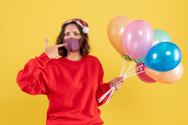 Front view young woman holding balloons on yellow