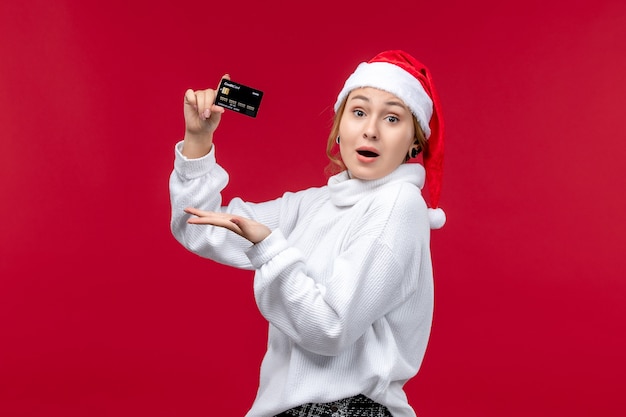 Front view young woman holding bank card on red floor red holiday money christmas