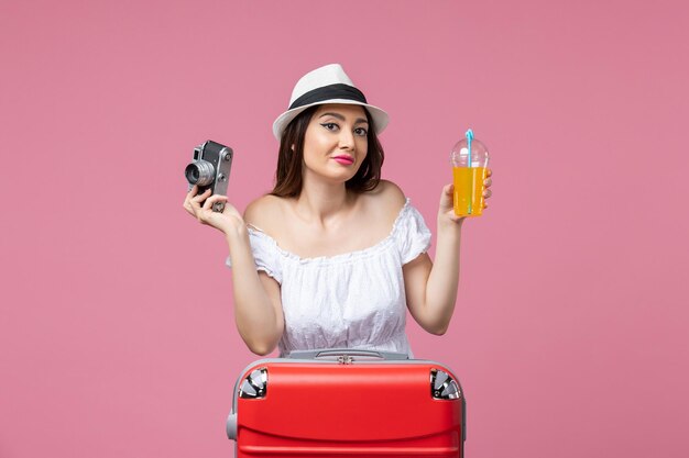 Front view young woman holding camera and cocktail on a pink wall color vacation trip heat summer voyage