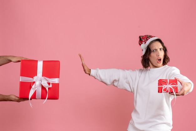 Free photo front view of young woman holding little present and not accepting gift from man on pink wall