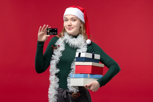 Front view young woman holding new year presents on a red background