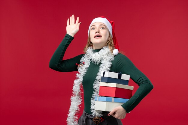 Front view young woman holding new year presents on red background