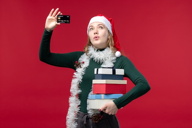 Free Photo front view young woman holding presents and bank card on a red background