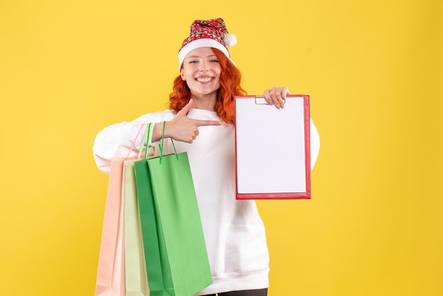 Free Photo front view of young woman holding shopping packages on yellow wall