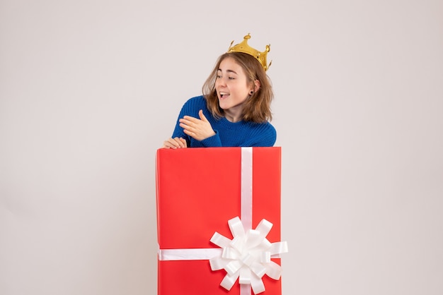 Front view of young woman inside red present box on white wall