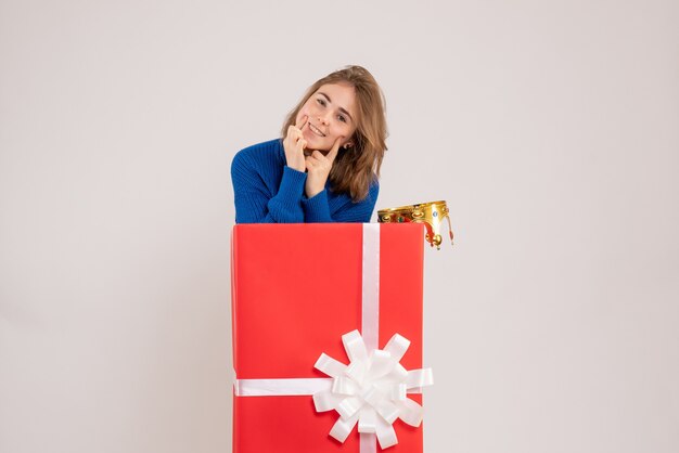 Front view of young woman inside red present box on white wall