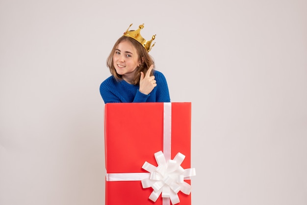 Front view of young woman inside red present box on white wall