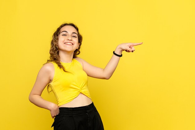 Front view of young woman laughing on yellow wall