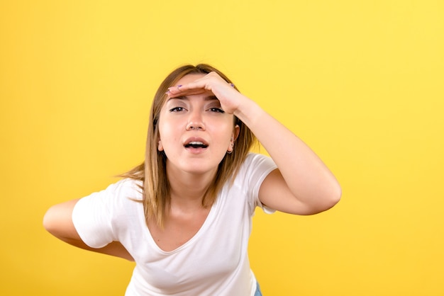 Front view of young woman looking at distance on yellow wall