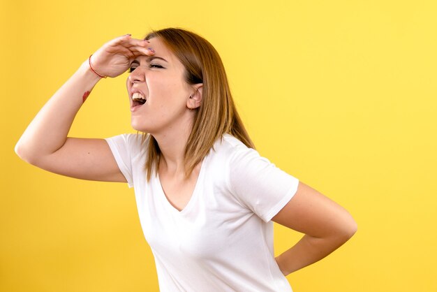 Front view of young woman looking at distance on yellow wall