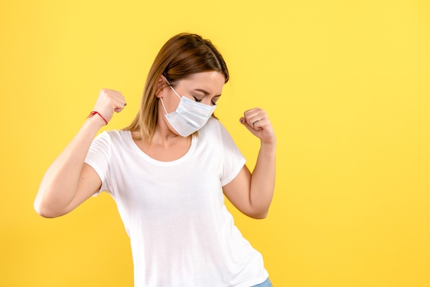 Front view of young woman in mask on yellow wall