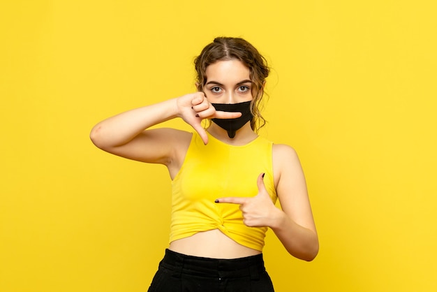 Free photo front view of young woman in mask on yellow wall