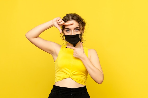 Free photo front view of young woman in mask on yellow wall