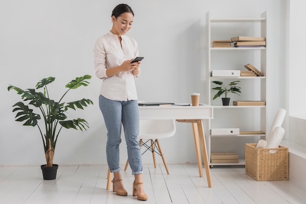 Front view young woman at office using mobile