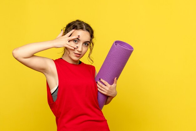 Front view of young woman posing with purple carpet on yellow wall