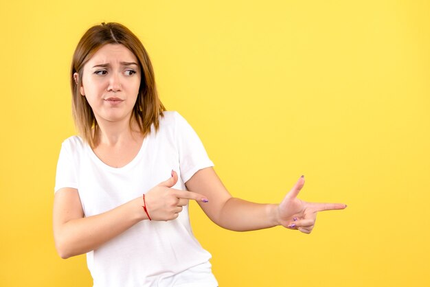 Front view of young woman posing on yellow wall