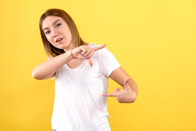 Front view of young woman showing size on yellow wall